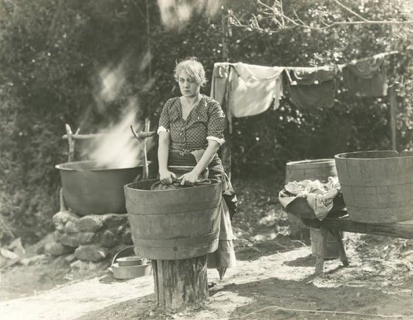 eine Frau wäscht ihre Wäsche von Hand vor 100 Jahren